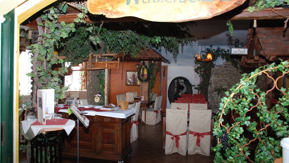 Gemütliches Restaurant mit weinartigem Dekor und gedeckten Tischen.
