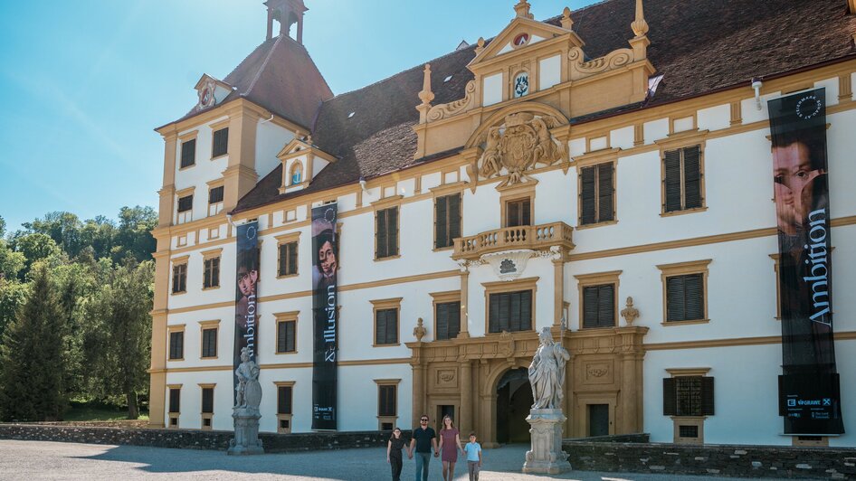 Besucher vor einem kunstvollen Schloss mit großen Bannern.