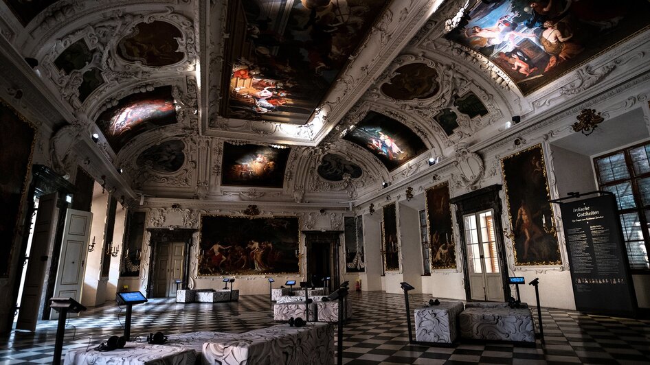 Ein eleganter Raum mit kunstvollen Deckenmalereien und Gemälden.