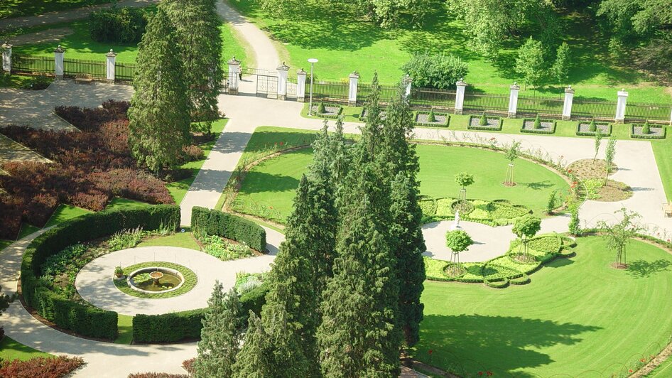 Schlosspark von Schloss Eggenberg in Graz mit gepflegten Grünflächen und Bäumen.