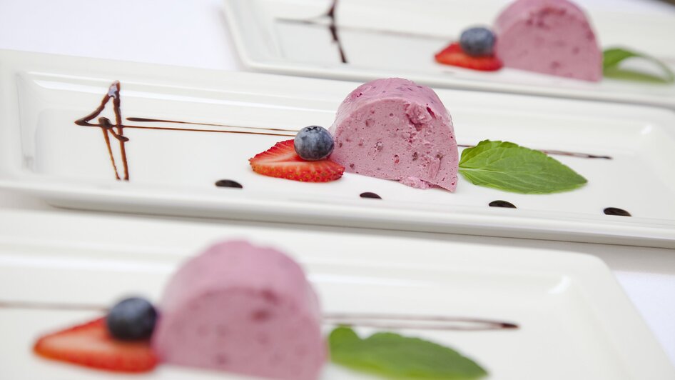 Dessert mit Beereneis, Erdbeeren und Minze auf Tellern.