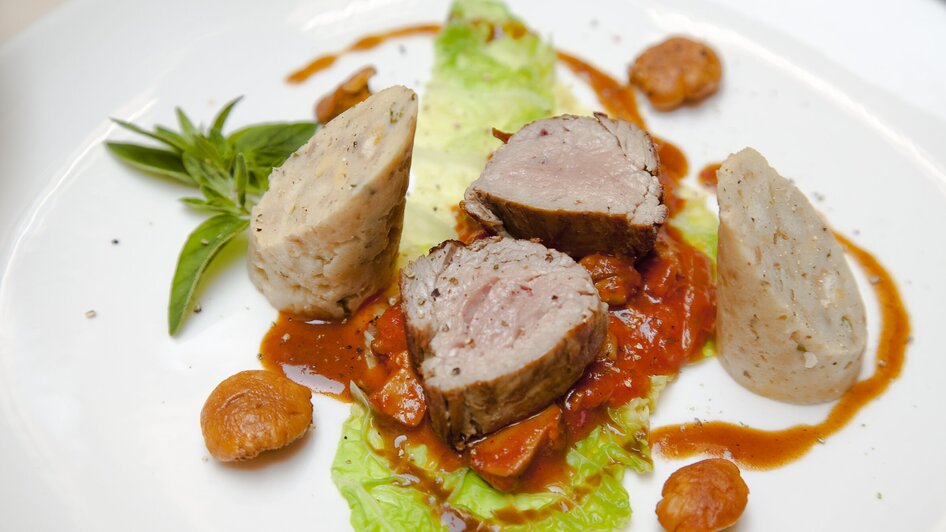 Ein kunstvoll angerichtetes Gericht mit Fleisch, Soße und Gemüse.