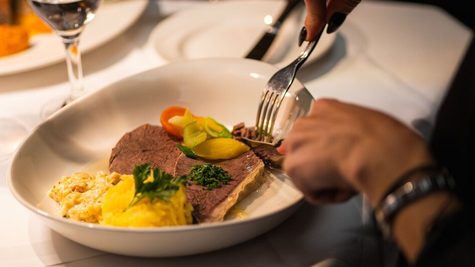 Ein Gericht im Gasthaus Stainzerbauer in Graz, das saftiges Fleisch und Beilagen zeigt.