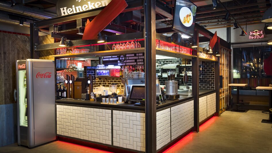 Bar mit Heineken-Werbung und Coca-Cola Kühlschrank im modernen Design.