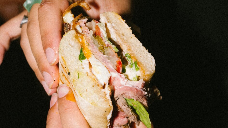 Eine Person hält ein Sandwich mit Rindfleisch und Salat. | © Bobby's Agency - Simon Bauer