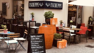 Gemütliche Außenansicht der Tscheppe Bar in Graz mit Outdoor-Sitzbereichen und einer Menü-Tafel. | © Tscheppe ums Eck