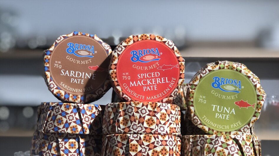 Verschiedene Briosa Gourmet Pâtés: Sardinen, Gewürzmakrele und Thunfisch auf einem Glasstand.