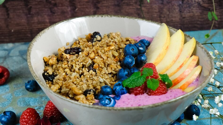 Schüssel mit Haferflocken, Beeren und Apfelscheiben. | © Mona Ramsenthaler