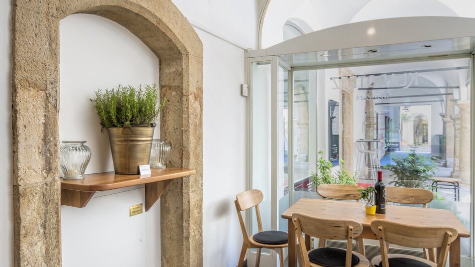 Gemütliche Ecke einer Weinbar mit Holzregal und Tisch. | © Klapotetz