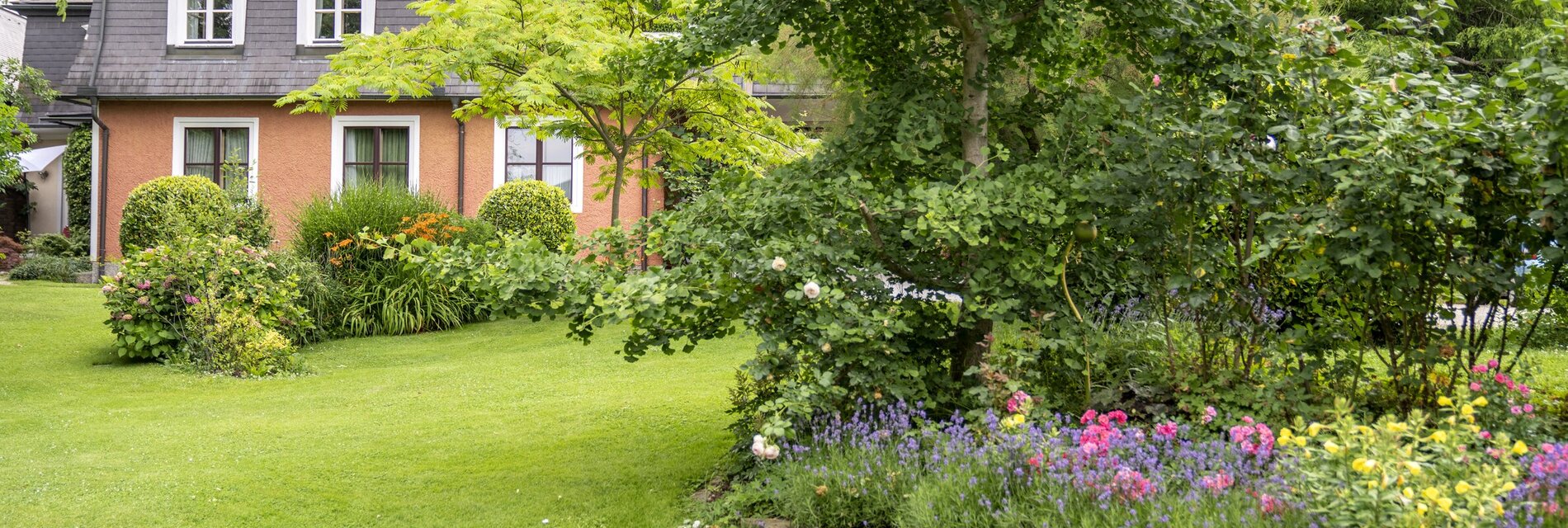 Garten mit Blumenbeet und Haus Anna im Hintergrund.