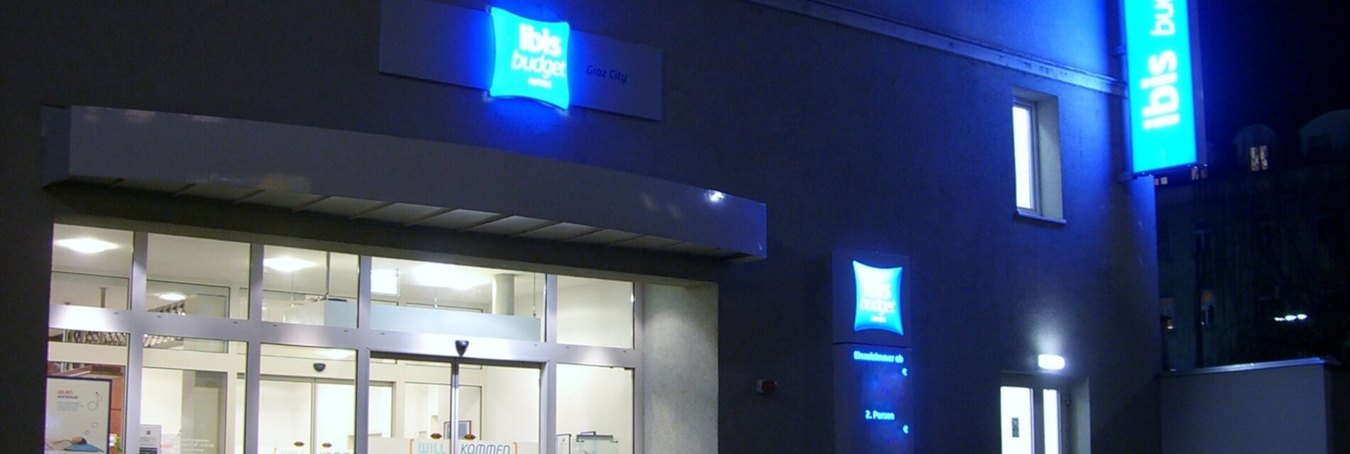 Das IBIS Budget Hotel Graz City mit leuchtenden Schildern bei Nacht.