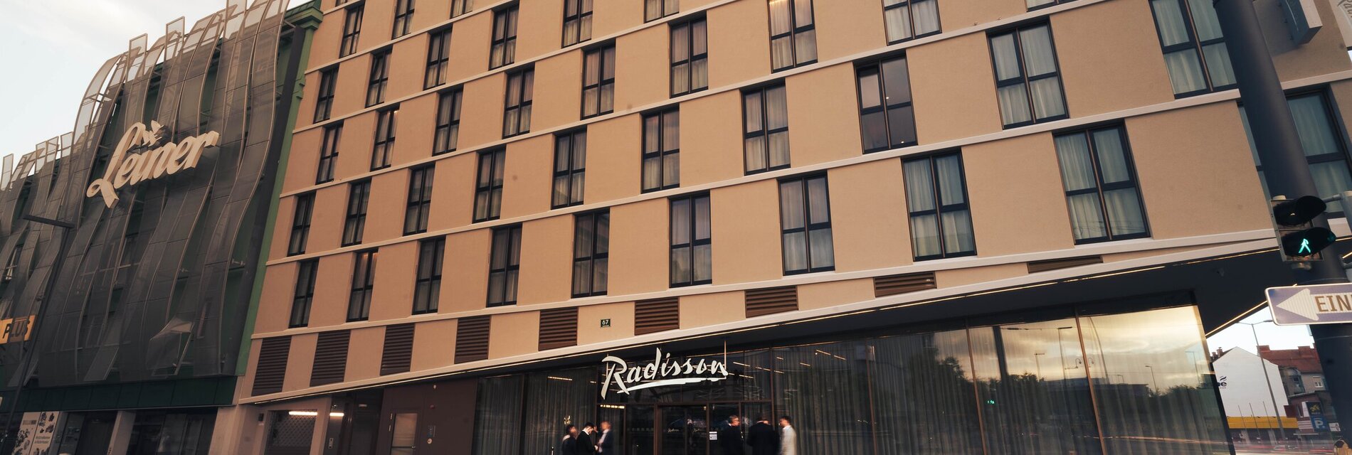Außenansicht des Radisson Hotels mit Gästen am Eingang.