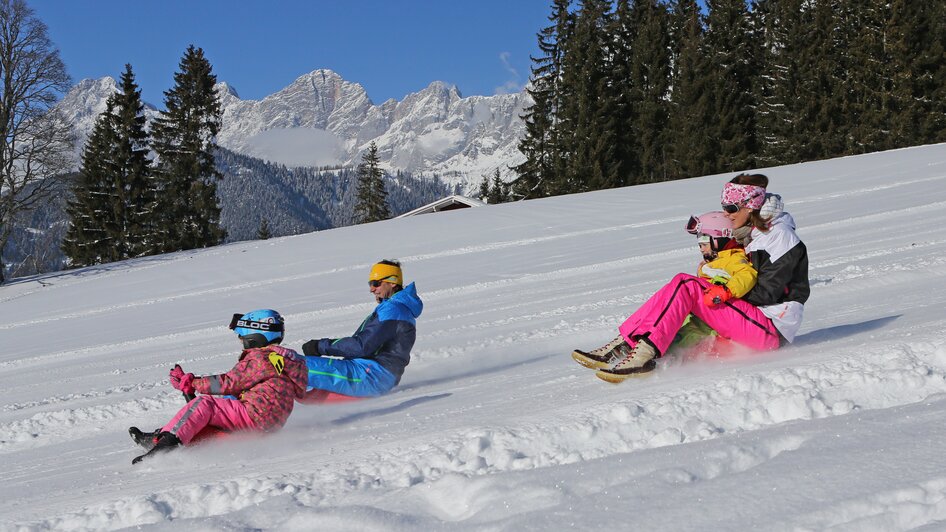 Familie beim Zipfelbobfahren.  | © Hans-Peter Steiner